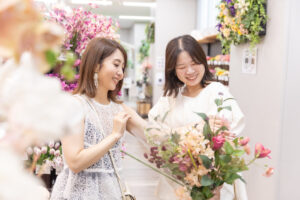 花屋で色とりどりのブーケを選びながら笑顔で会話する女性2人